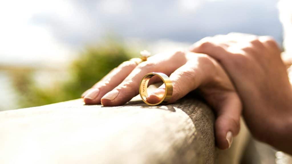 A woman holding a wedding ring with her finger.