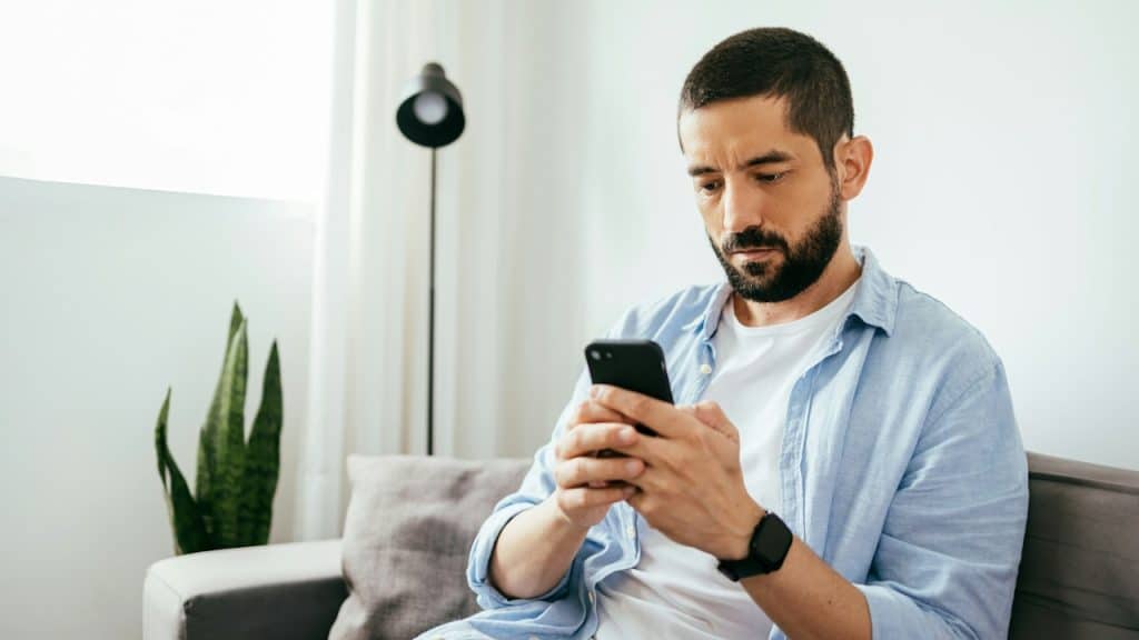 A man with a glum expression looking at his phone.