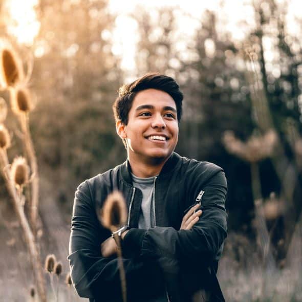 The man is smiling brightly while standing in the middle of the field.