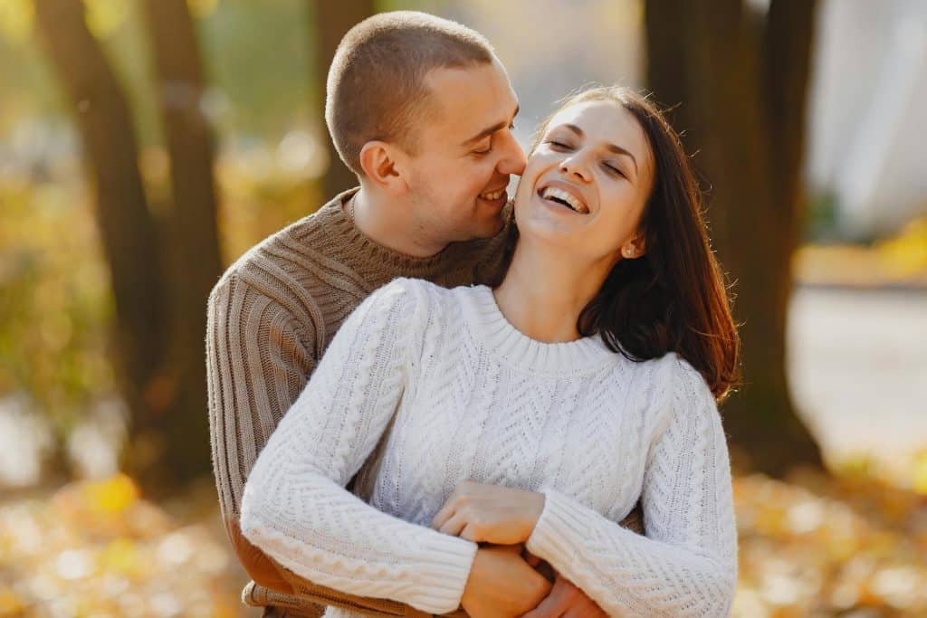 The man is hugging the woman while spending outdoors in autumn.