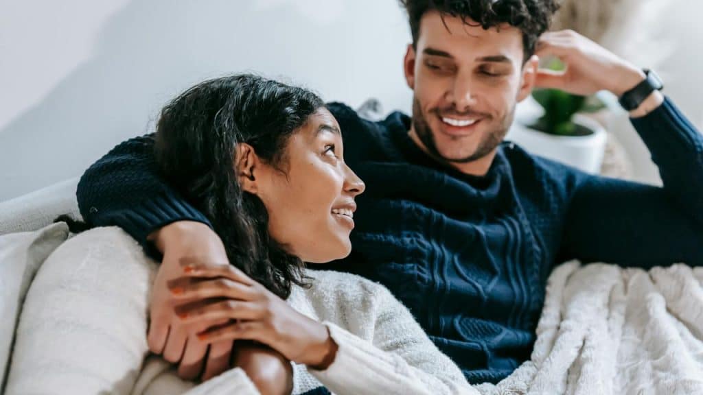 A couple relaxing on a couch and smiling at each other.