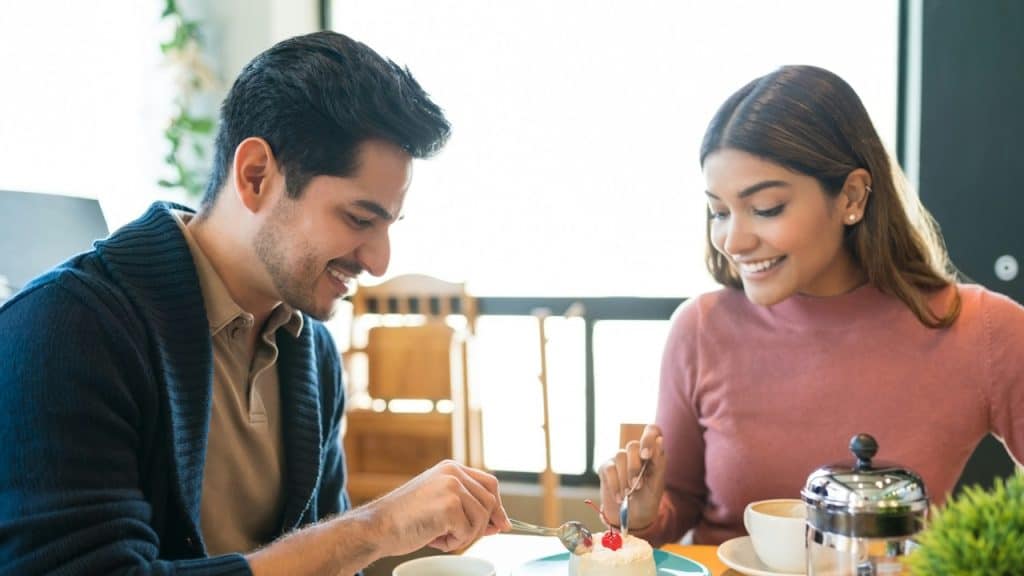 A couple sharing dessert at a table in a cafe.
