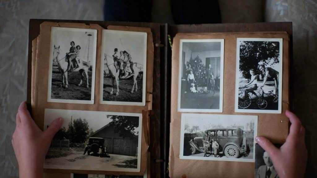 Person opening photo album displaying grayscale photos.