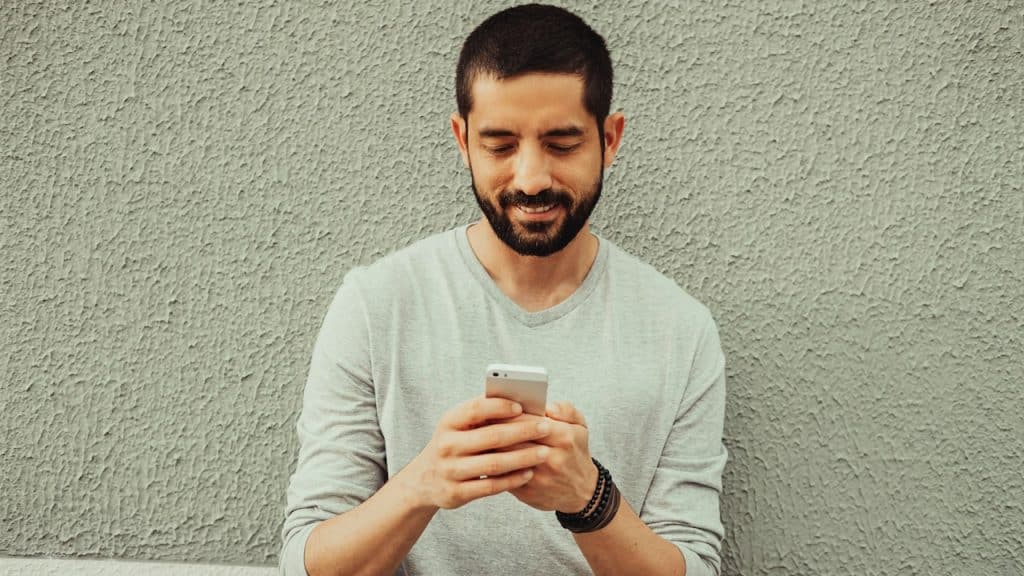 A man smiling while using his phone.
