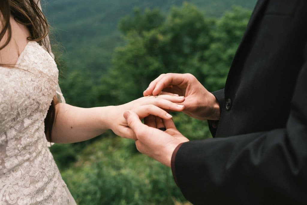 The man is putting the ring in the woman’s finger.
