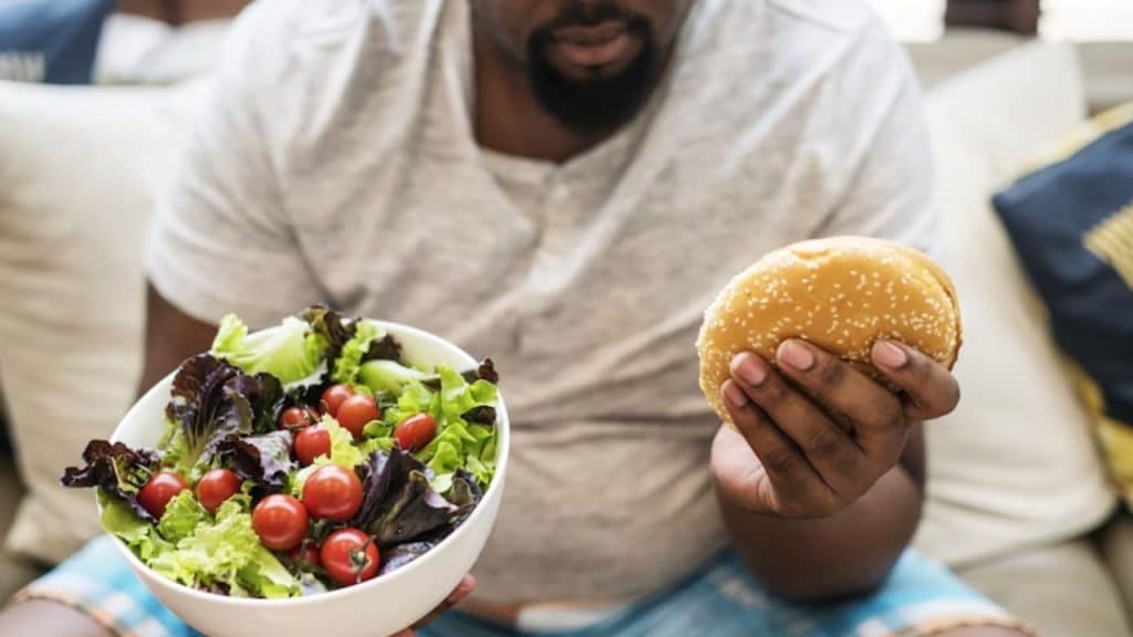 Man choosing between fast food and a salad