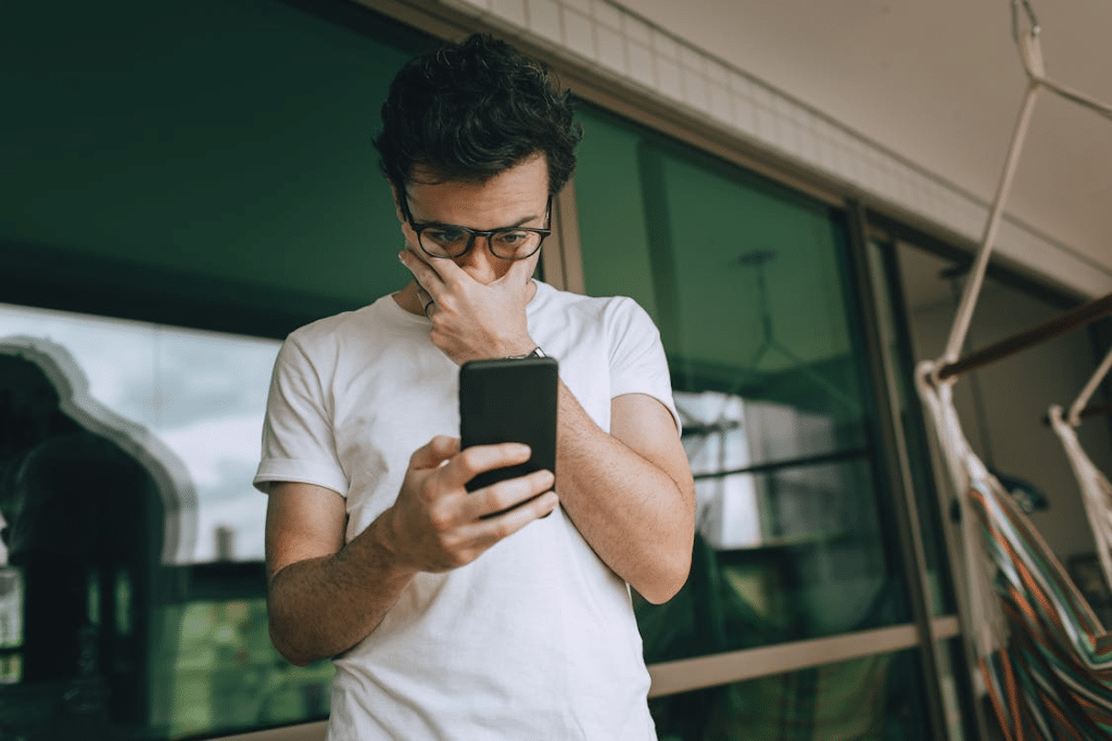 Man Looking at Phone with Hand on Face