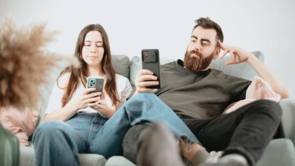 Couple sitting on the couch, both on their phones