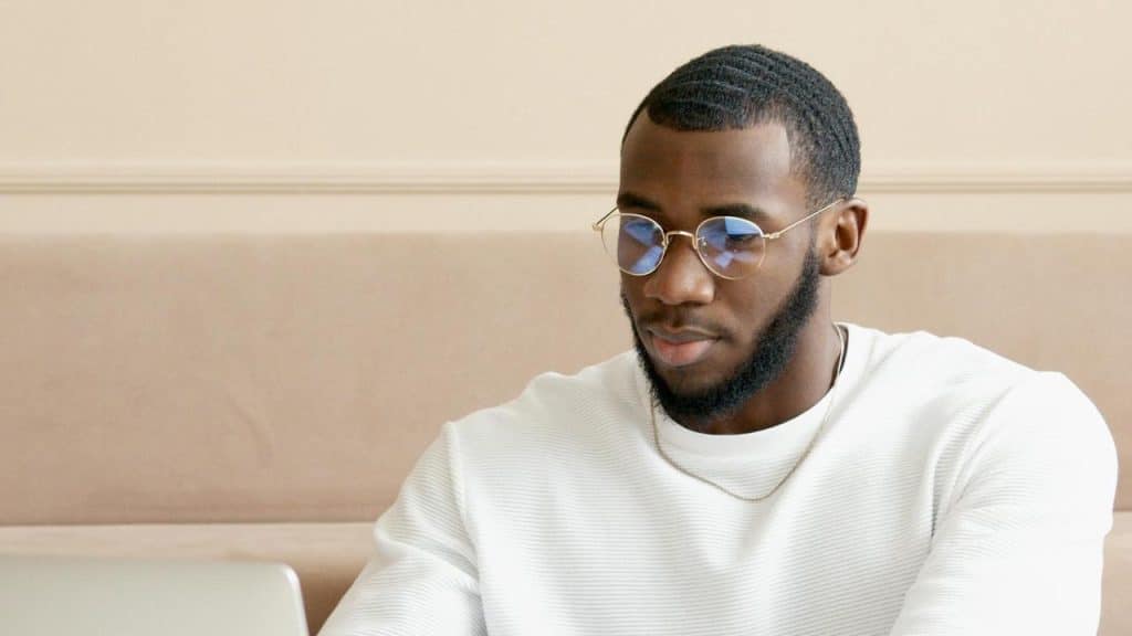 A man in glasses and a white shirt working on a laptop.