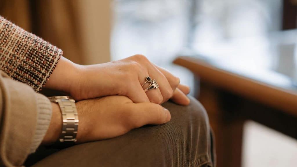 A close-up of a couple holding hands while sitting together.