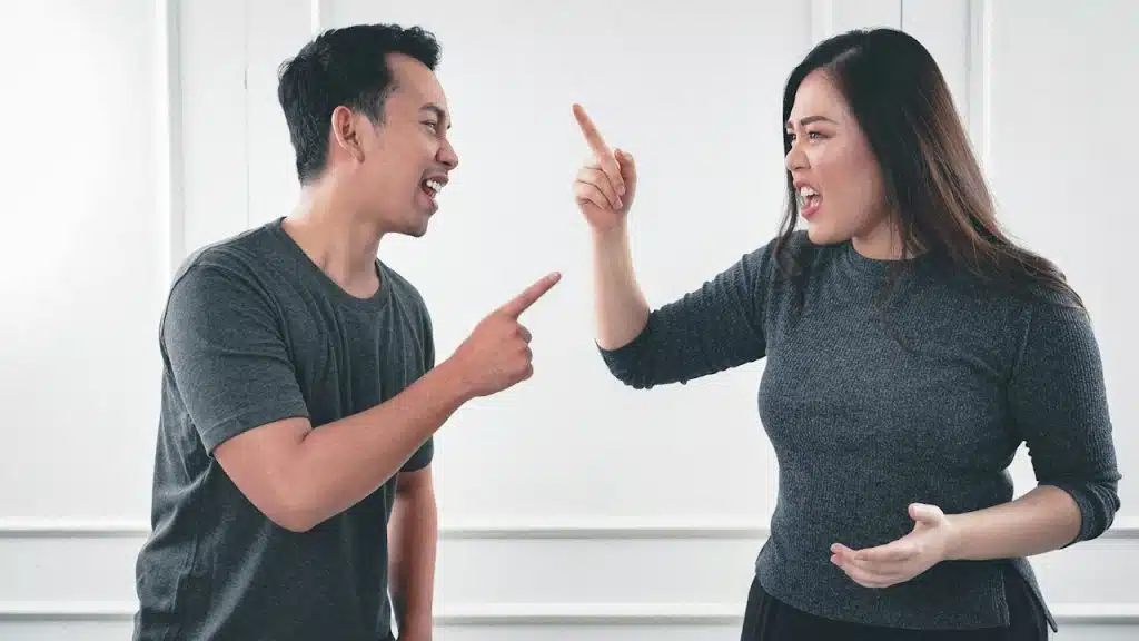 A man in a gray shirt arguing with a woman in black shirt.