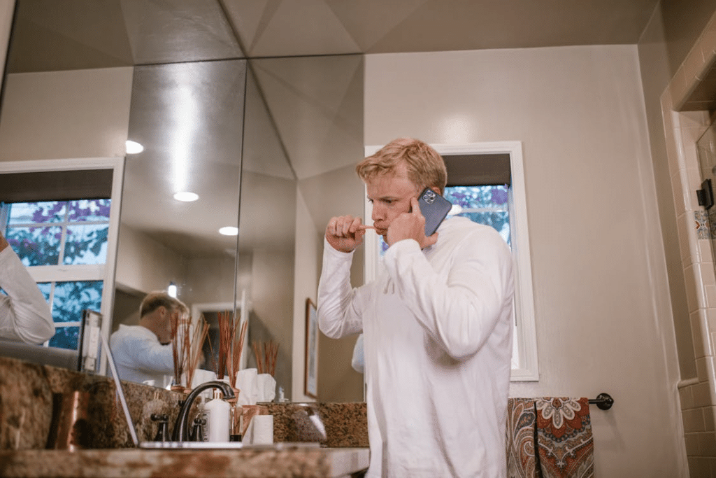 A Man Brushing His Teeth while Looking at a Laptop