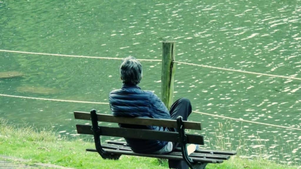 Man sitting peacefully on a bench near a lake