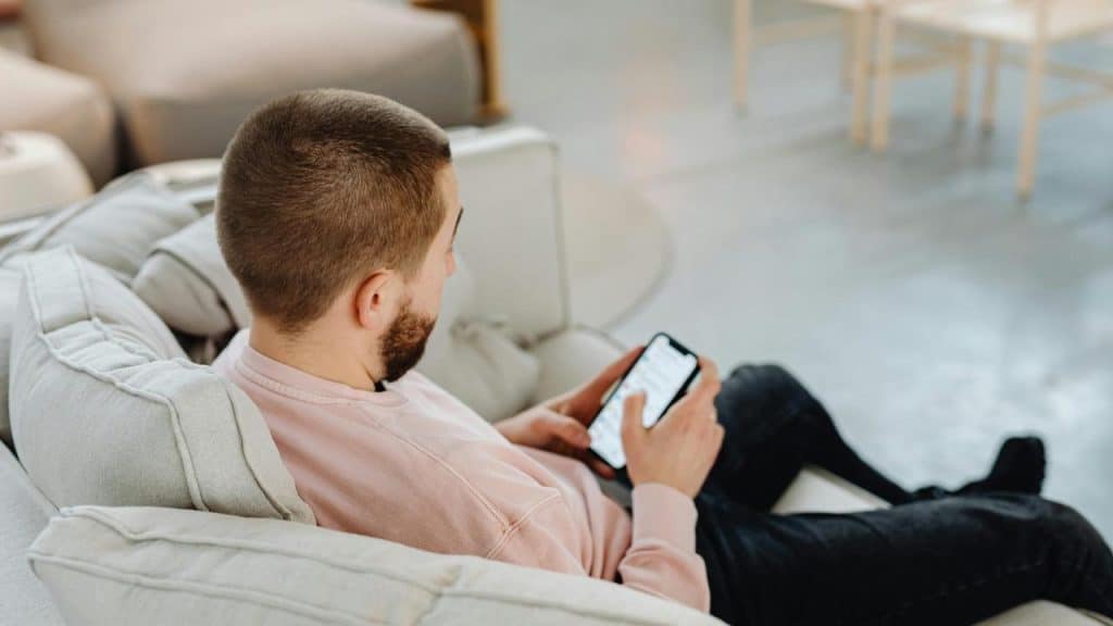 A man sitting on a couch using his smartphone.