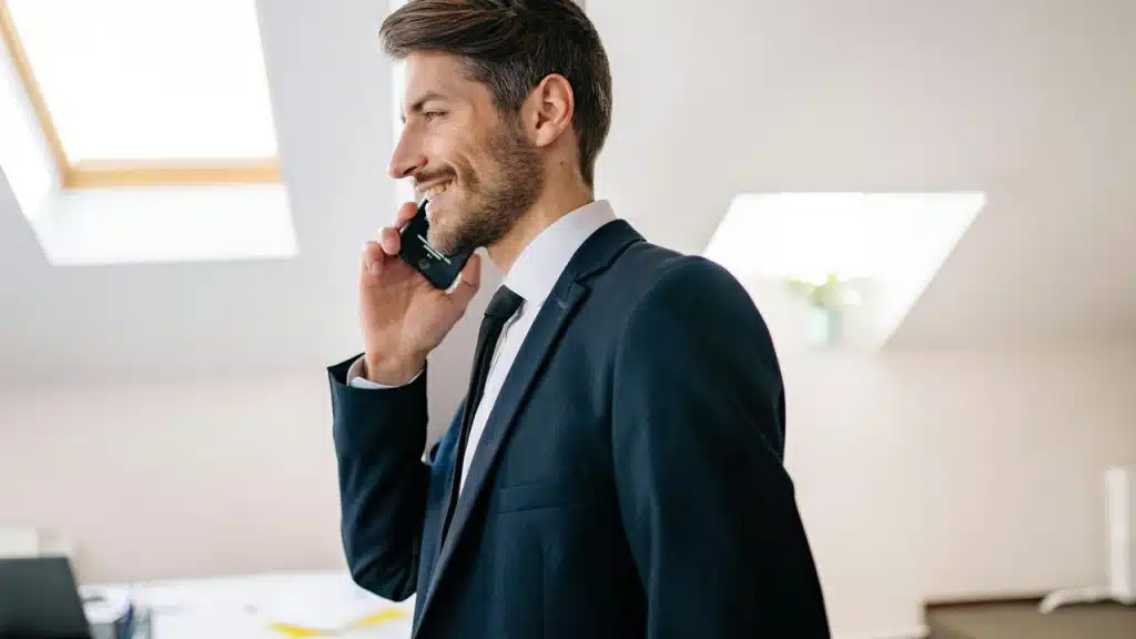 A man in a suit smiling while talking on his phone.