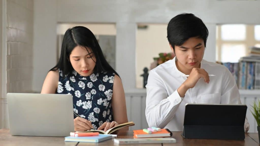 Two people, a woman and a man, are focused on work at a wooden table.