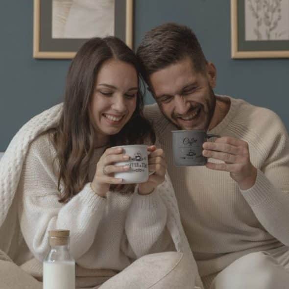 A couple smiling at each other over morning coffee