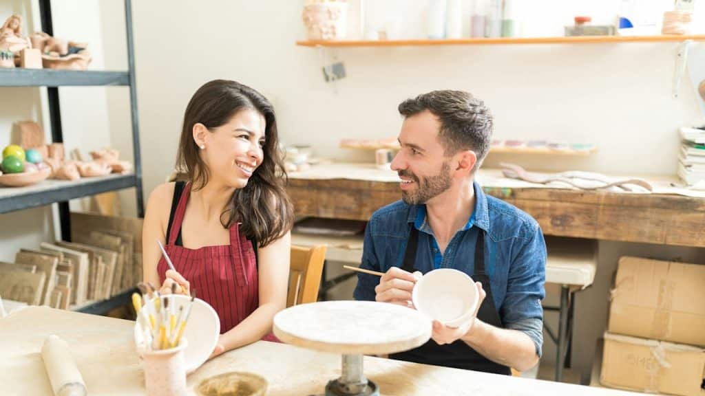 A couple having fun during a pottery date in a workshop.