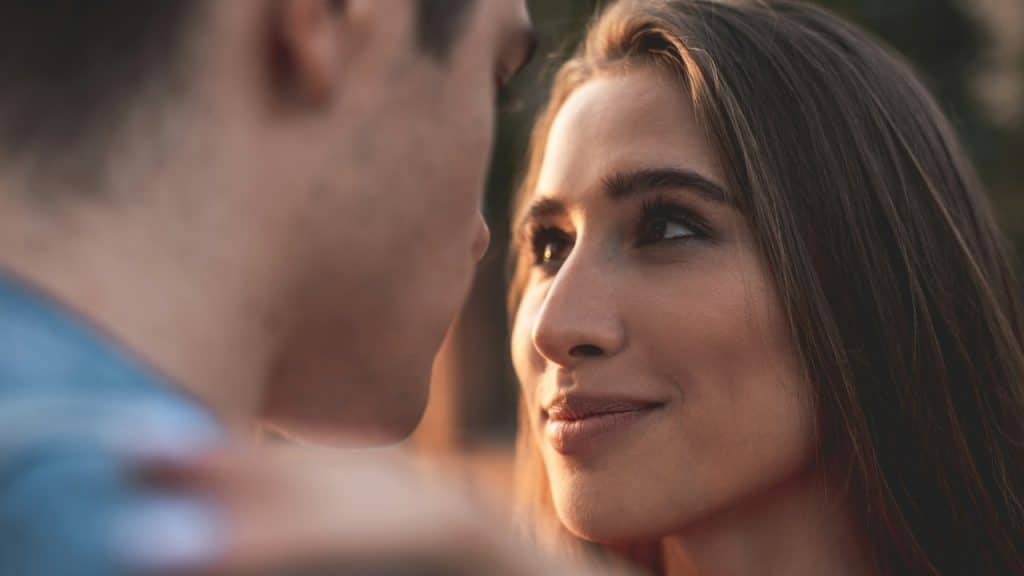 A woman gazing into her man’s eyes lovingly while smiling.