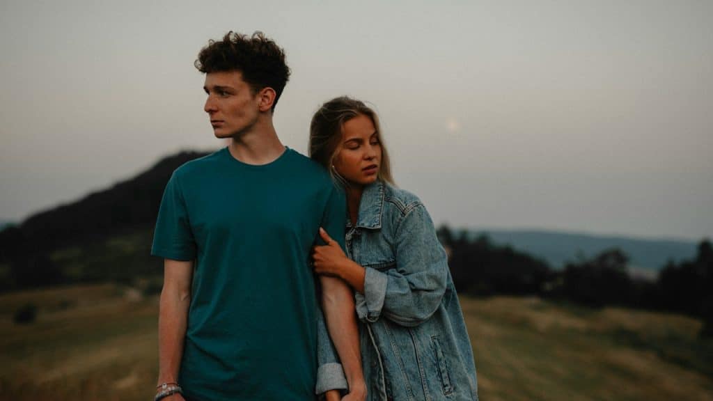 A couple standing with each other but looking away from each other.