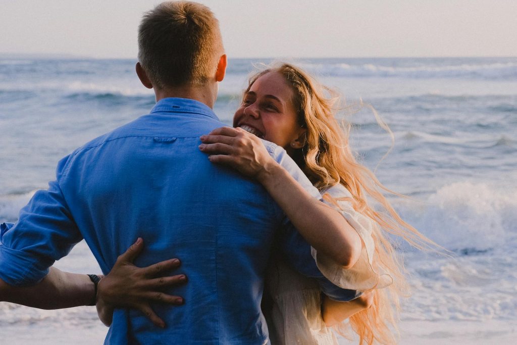 The couple is hugging at the beach.