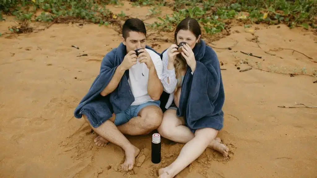 A man and a woman sitting in the sand.
