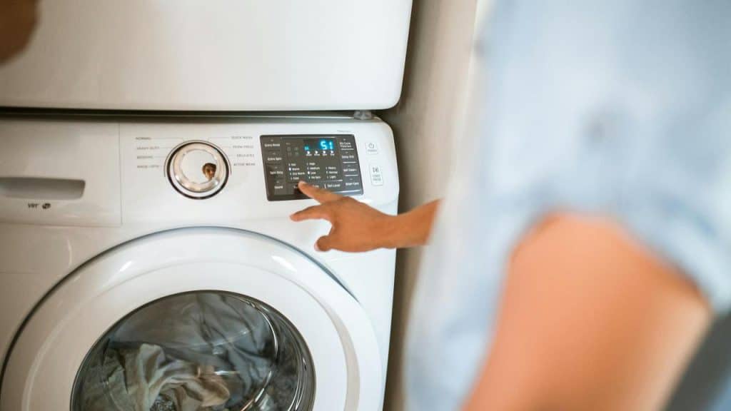 A person pressing buttons on a washing machine.