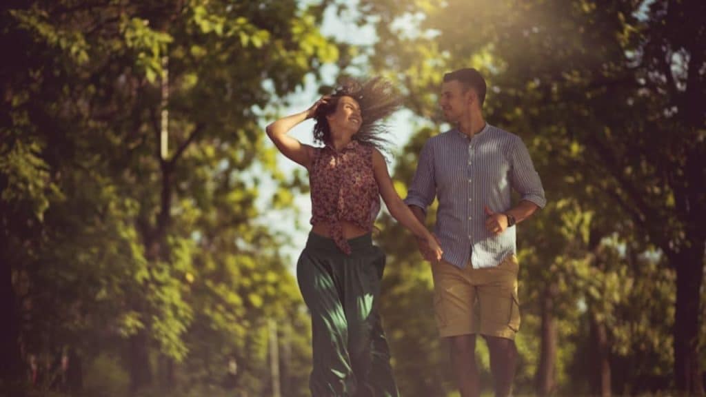 Couple walking hand in hand outdoors, smiling together