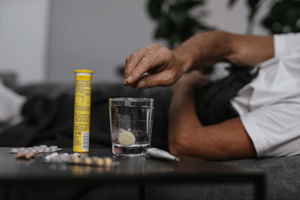 Person Putting Medicine on the Glass of Water