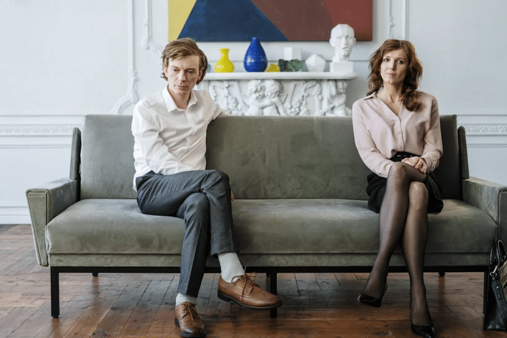 Woman in White Dress Shirt and Black Pants Sitting on Gray Couch