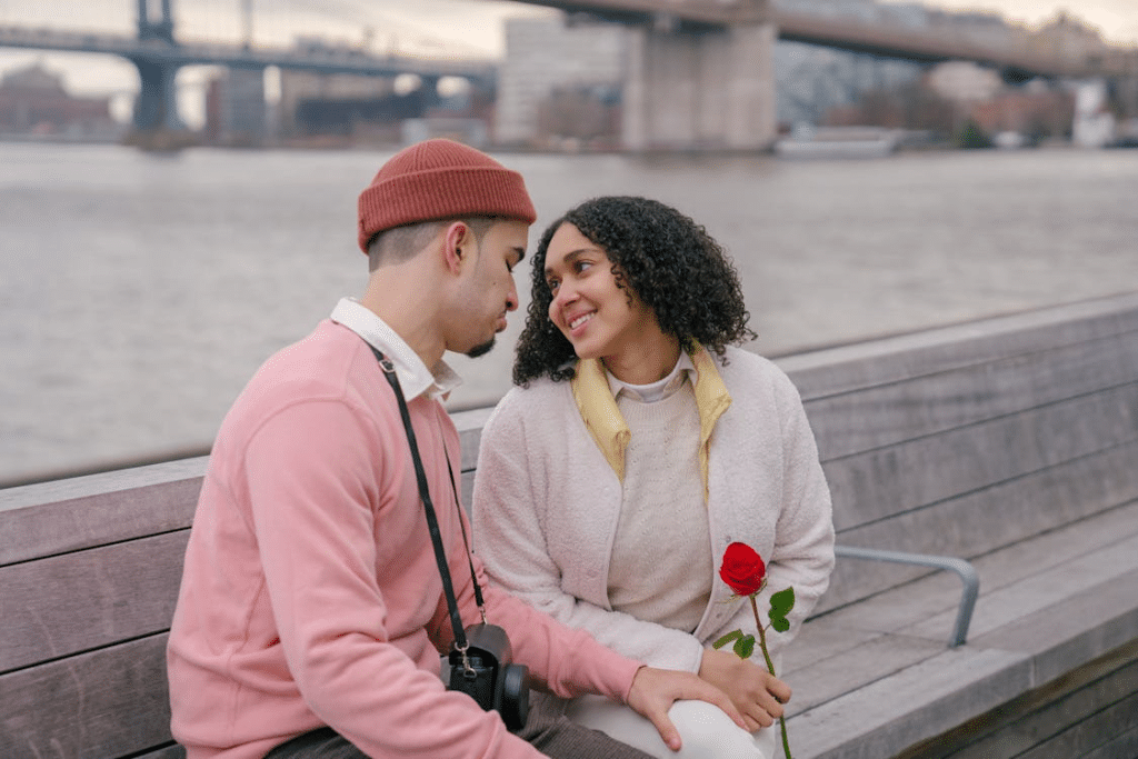 Hispanic couple with rose sitting on embankment