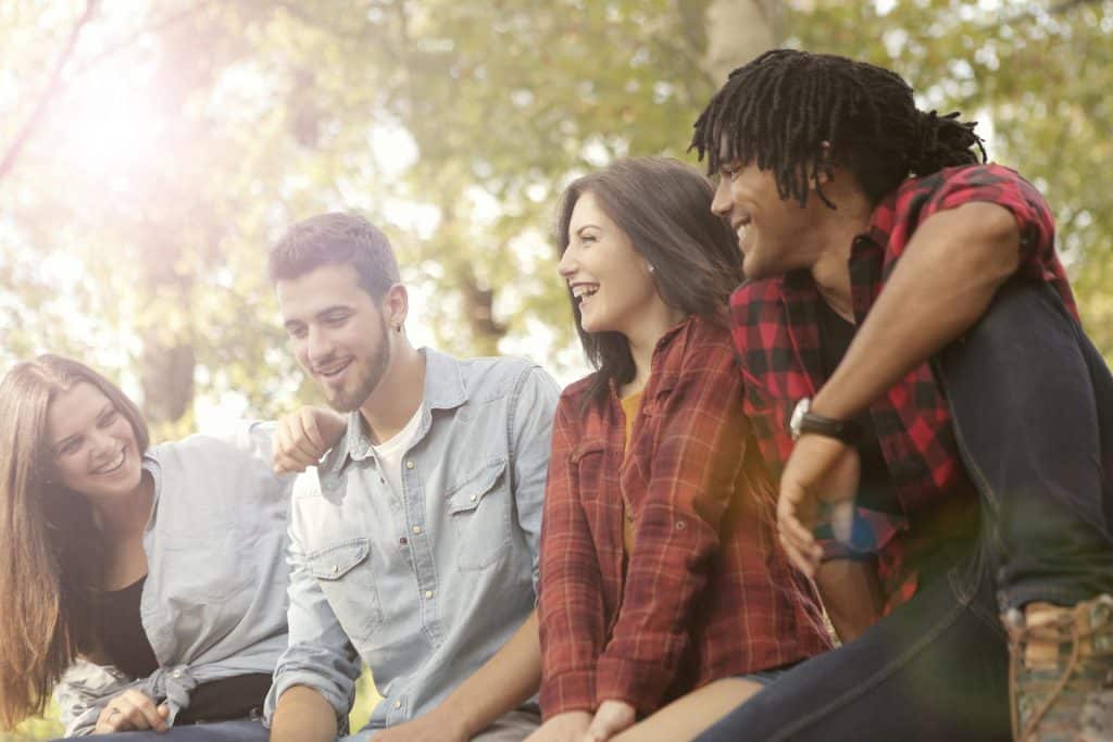 The friends are laughing while sitting outdoors.