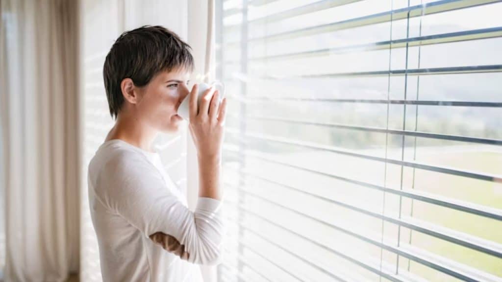 Woman staring out of a window with a blank expression
