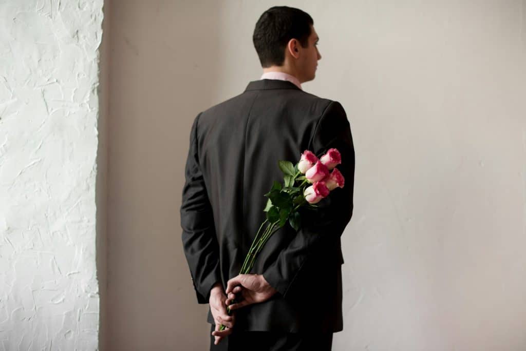 A man in a suit holding a bouquet of flowers.