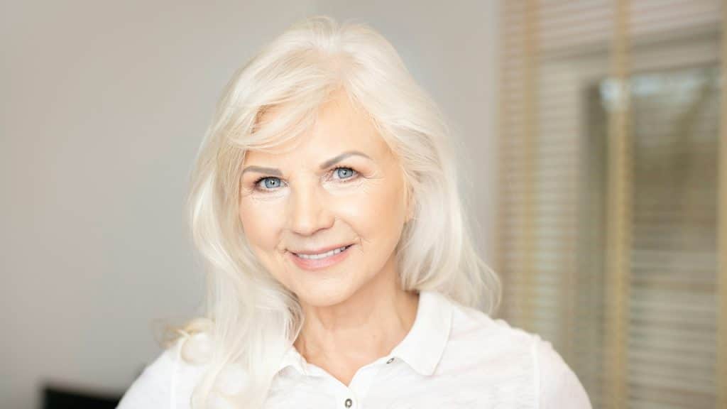 An older, attractive, white haired woman smiling at the camera.
