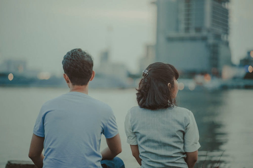 Man and Woman Watching Body of Water and Concrete Buildings