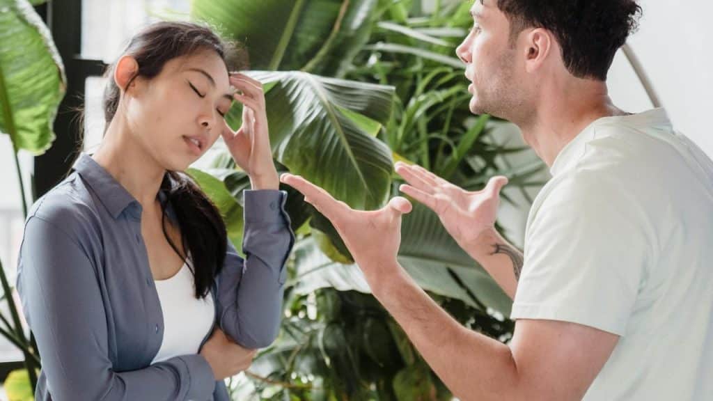 A woman looking frustrated while a man gestures during an argument.