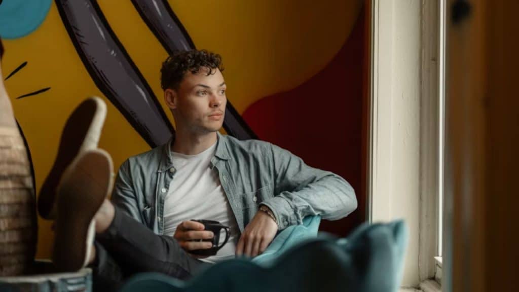 A man sitting on a couch,feet raised, avoiding eye contact