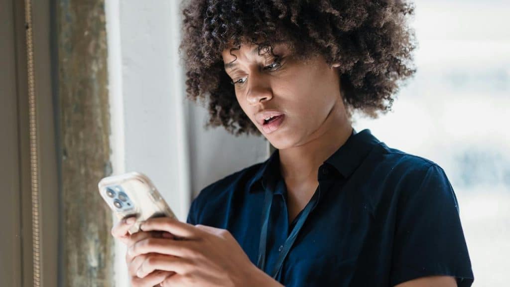 A woman looking at her phone with a concerned expression.
