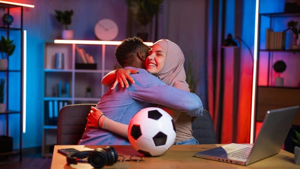 A girl with a hijab hugging an African American man.