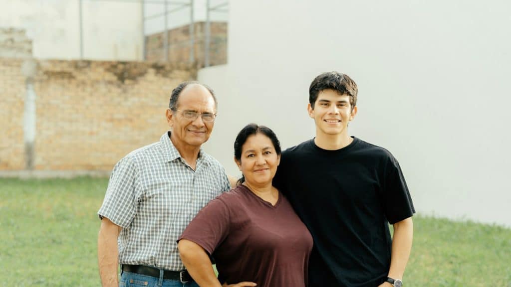 A young man posing for a picture with his parents.