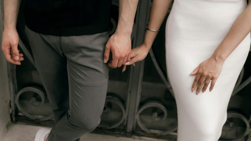 A couple standing close together holding hands.