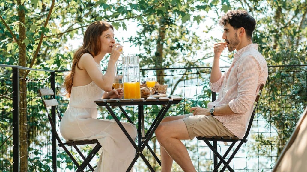 A man and a woman sitting at a table on a deck.