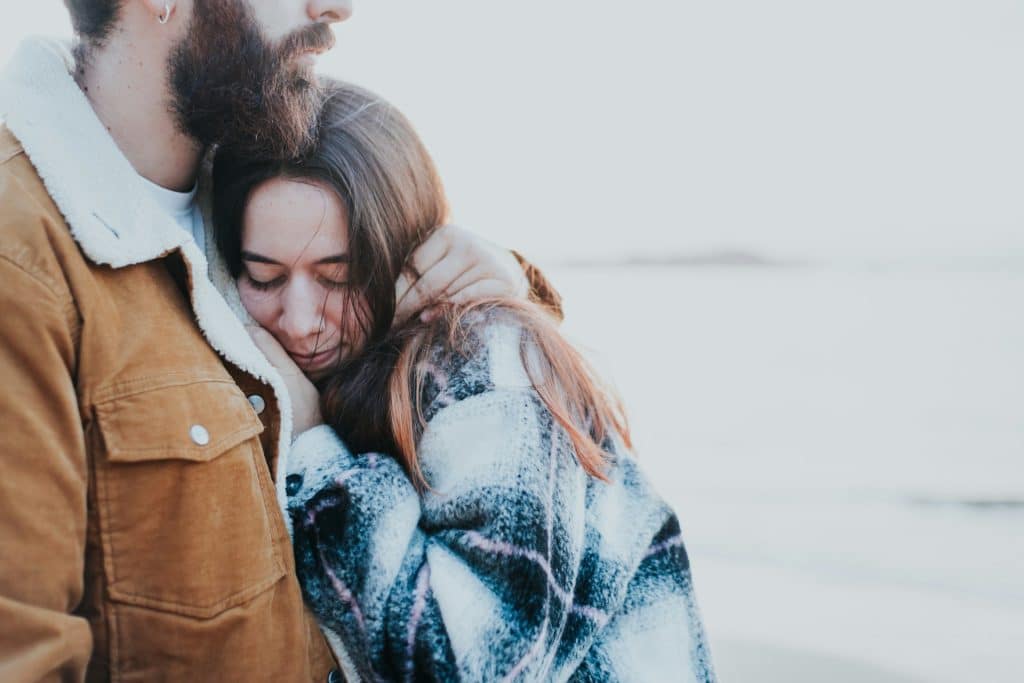 The couple is hugging on the beach.