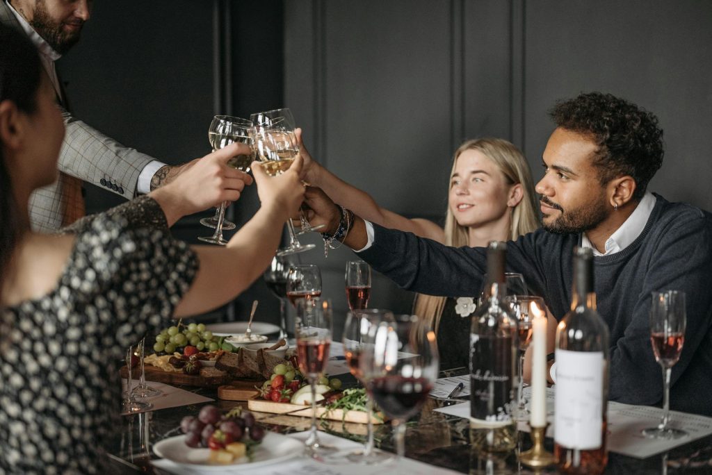 The people at the dinner table are holding glasses of wine.