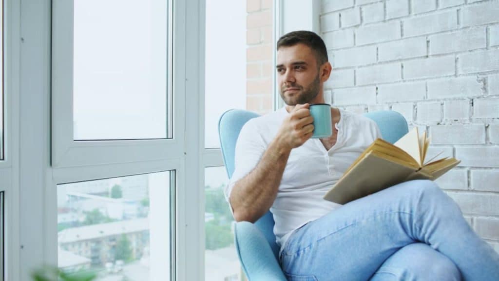 Man enjoying a quiet moment reading a book by the window