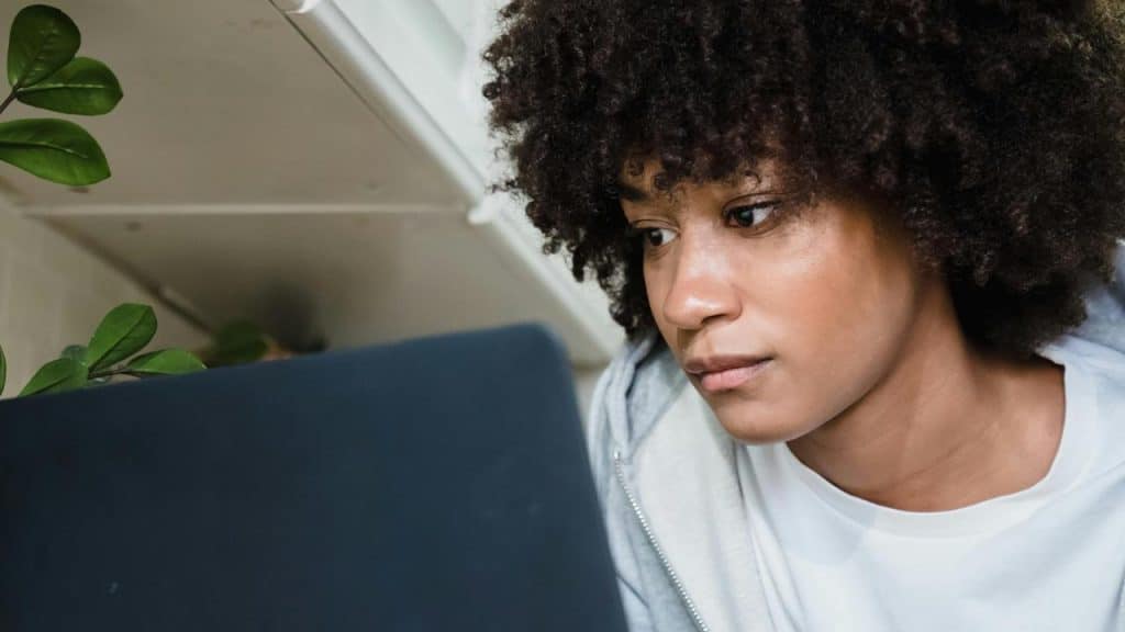 A woman with curly hair focused on a laptop screen.
