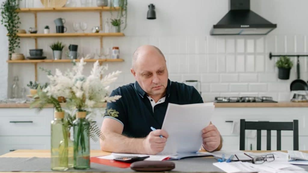 Man reviewing bills at the kitchen table