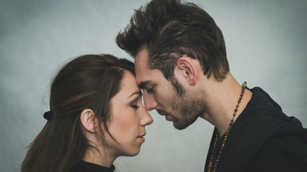 A couple with closed eyes touching foreheads.