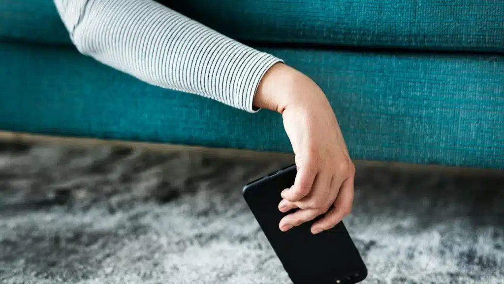 A hand holding a phone while it is on the ground.